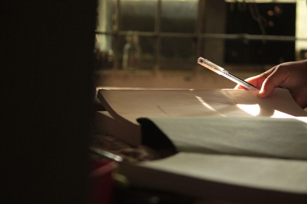 Notebook and pen beside a cup on a table in soft daylight