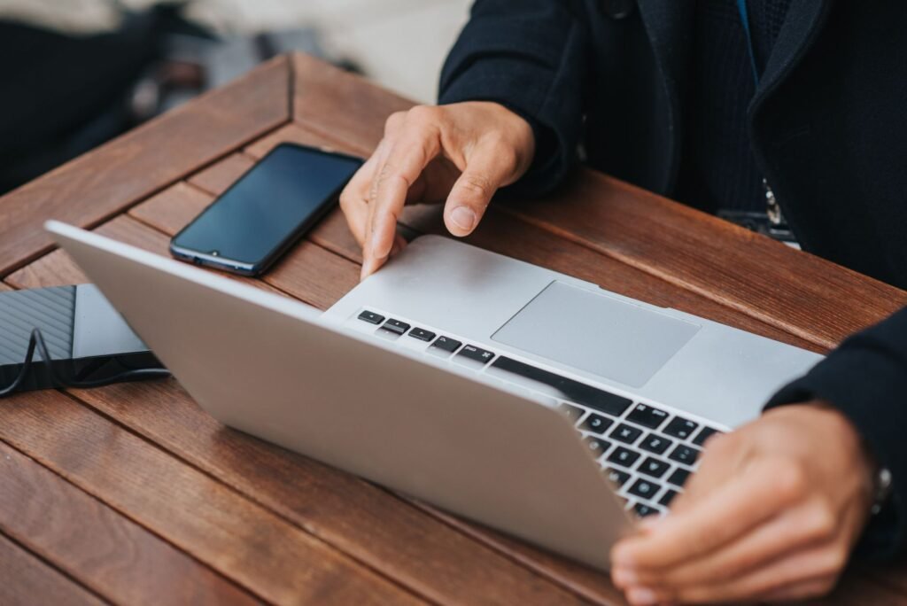 A smartphone and laptop on a wooden table in soft daylight, representing browsing an online directory