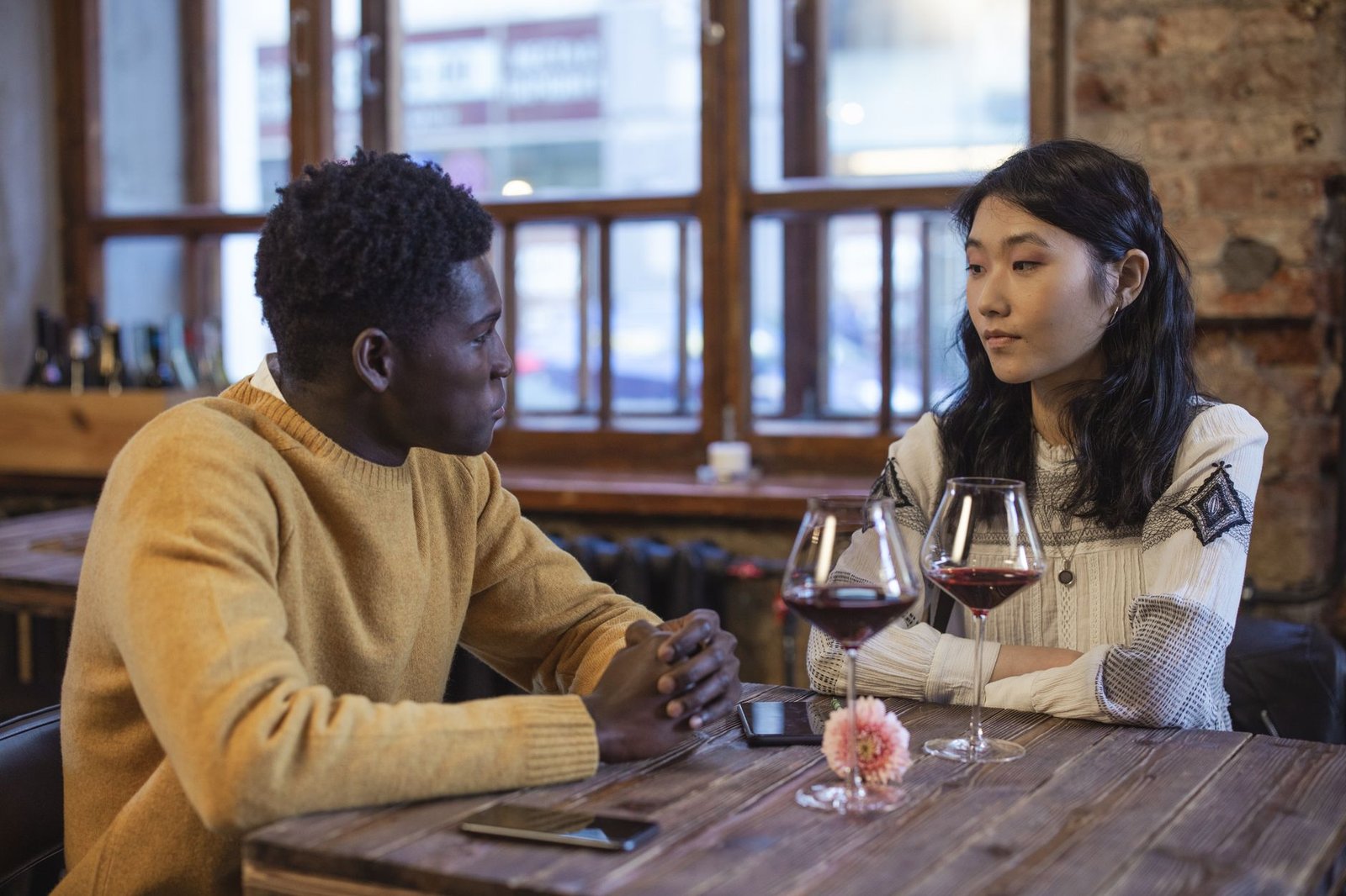 A diverse couple enjoying wine and conversation in a rustic café setting.