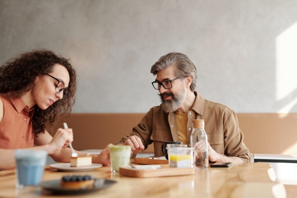 Two people in calm conversation at a table in a modest indoor setting