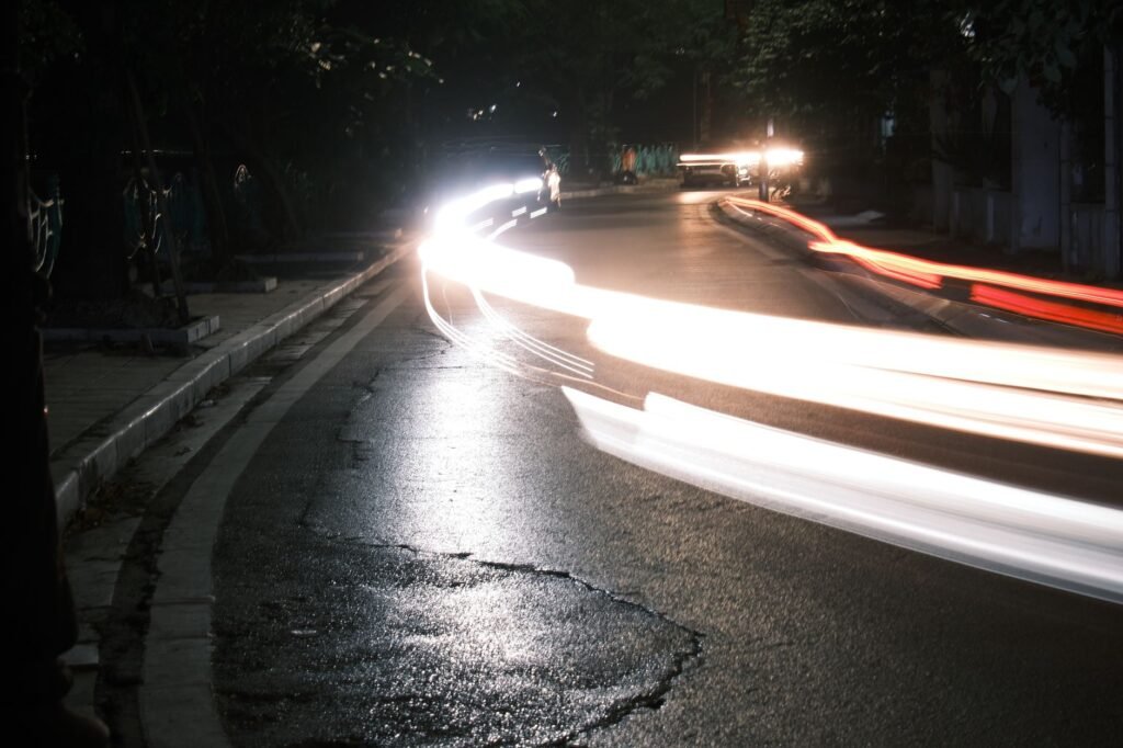Long exposure shot capturing vibrant light trails of vehicles on a city street at night.