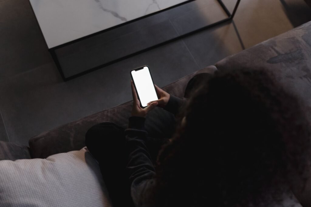 Person browsing a directory on a smartphone in a simple guesthouse room