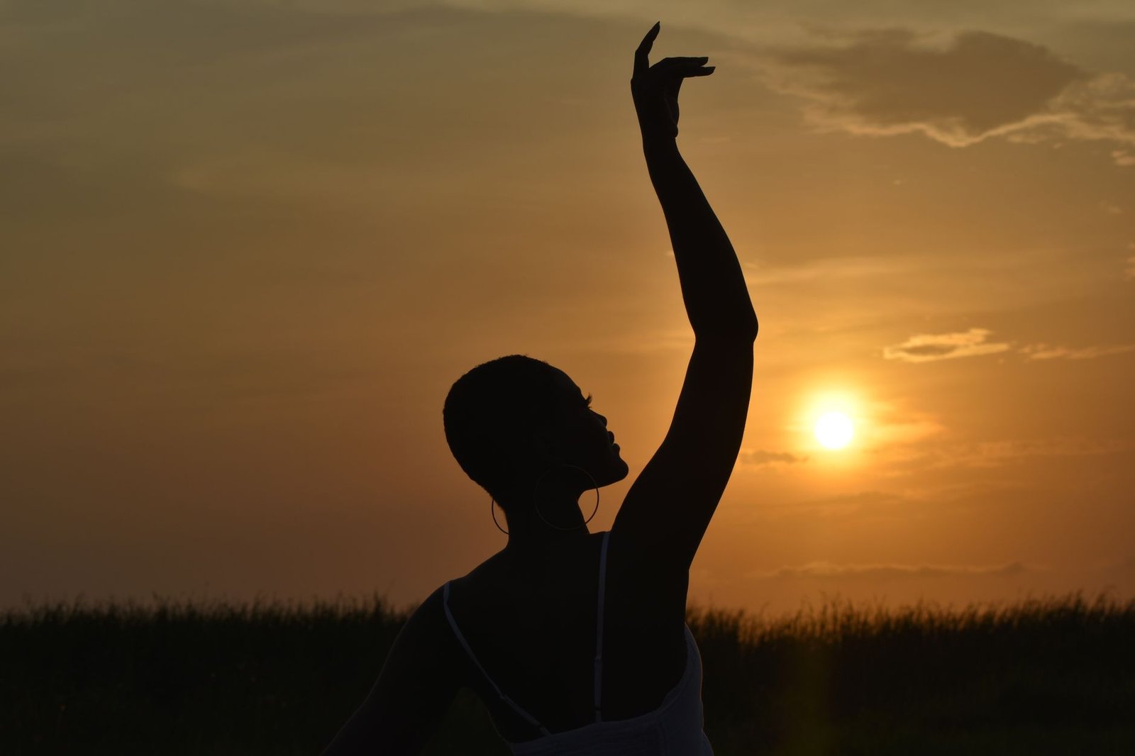 Graceful silhouette of a woman dancing against a vibrant sunset in Accra, Ghana. Captures elegance.
