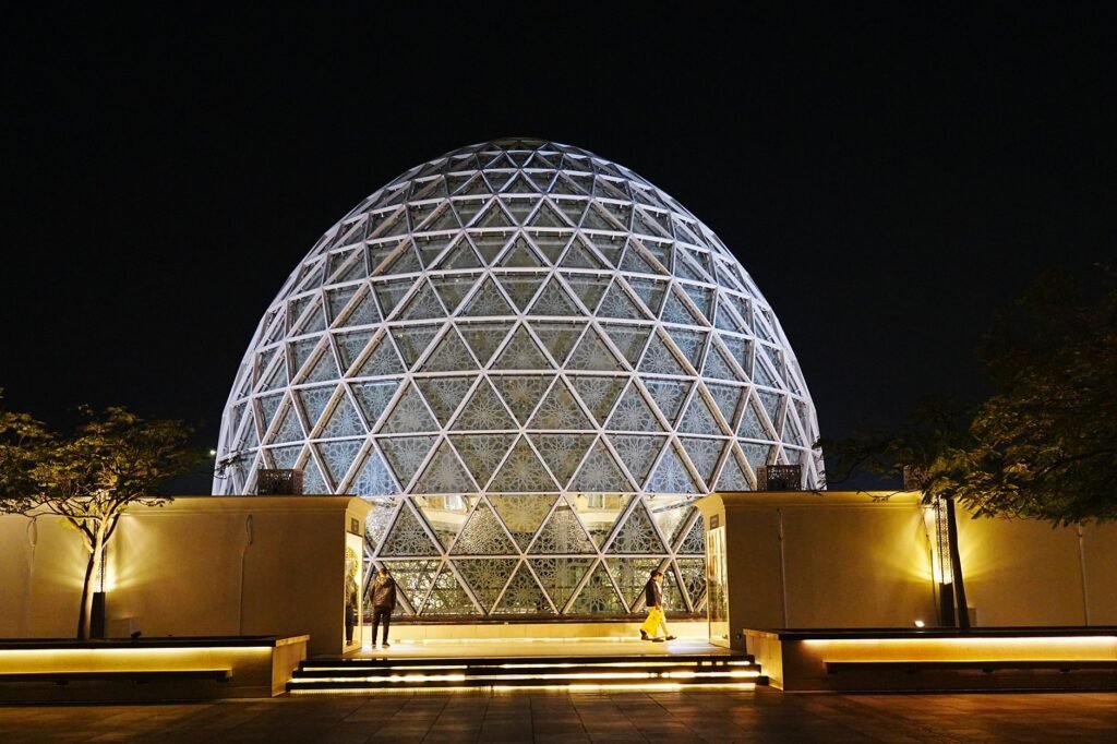 Illuminated geometric dome structure in Abu Dhabi, showcasing modern architecture at night.