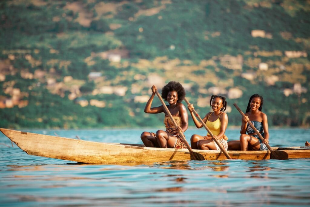 Three young women paddling a boat on a serene river in Accra, Ghana.