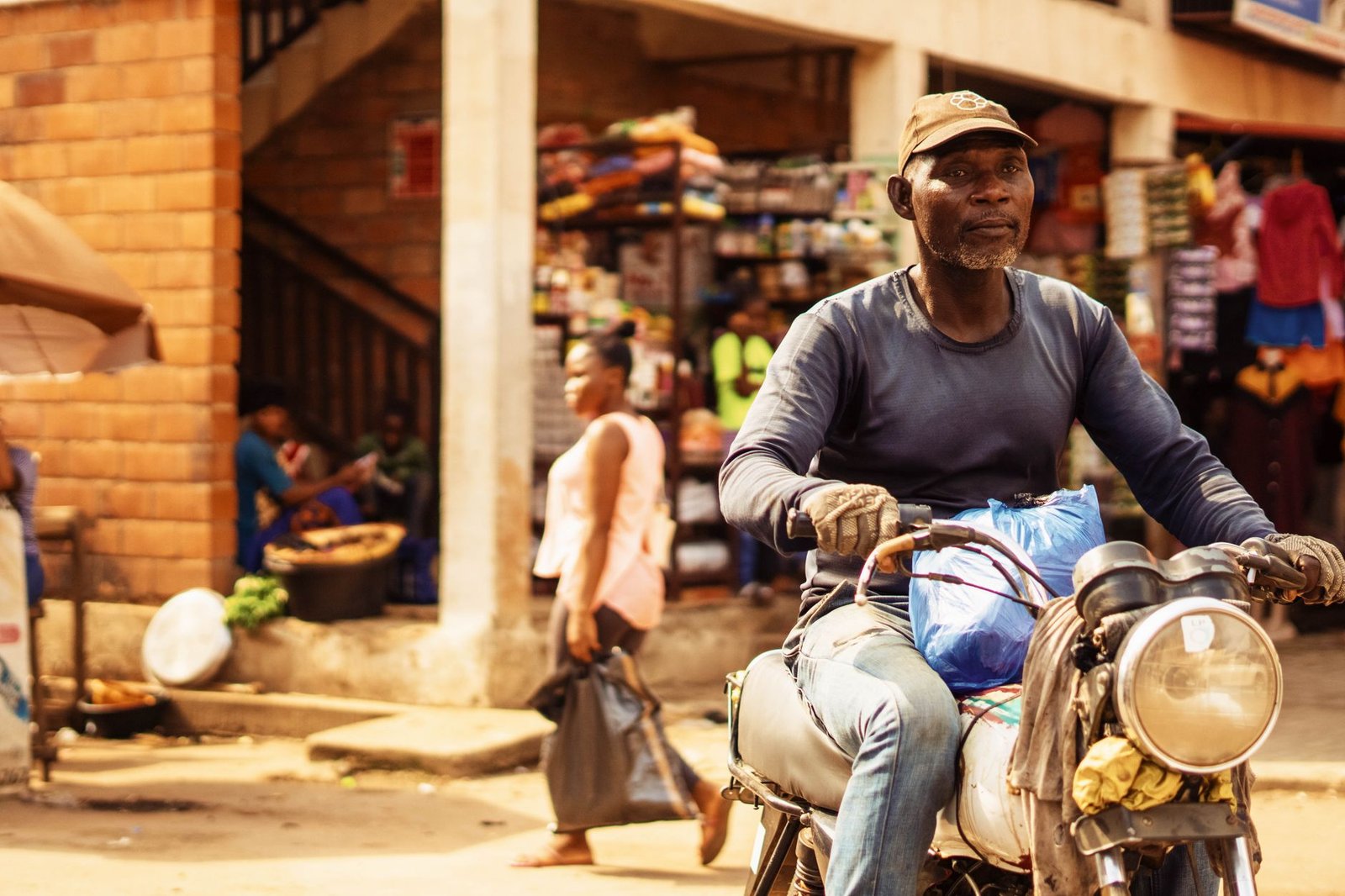 A motorcyclist navigates a bustling outdoor market scene, capturing urban life.