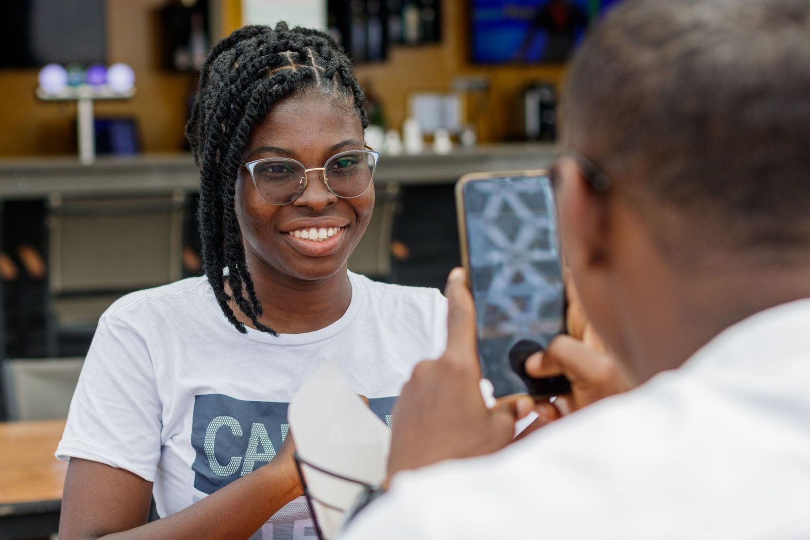 A joyful moment in an outdoor restaurant in Accra, Ghana, capturing a friendly interaction.