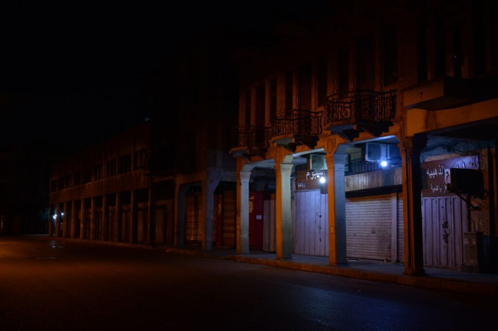 A quiet urban street with closed illuminated shops at night.