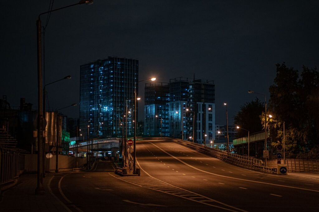 A modern urban street at night featuring illuminated buildings and an empty road, capturing serene city living.
