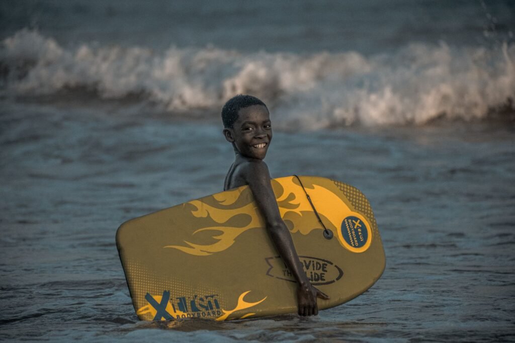 A cheerful child surfing at the beach in Takoradi, Ghana, showcasing vibrant summer fun.
