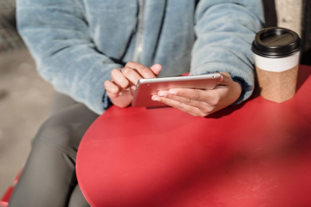 Person reading a listing on a smartphone at a wooden table in daylight
