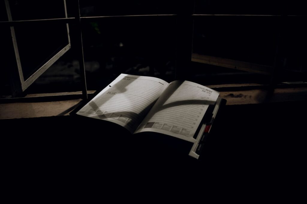 Travel notebook and phone on a table beside a guesthouse window while planning a trip