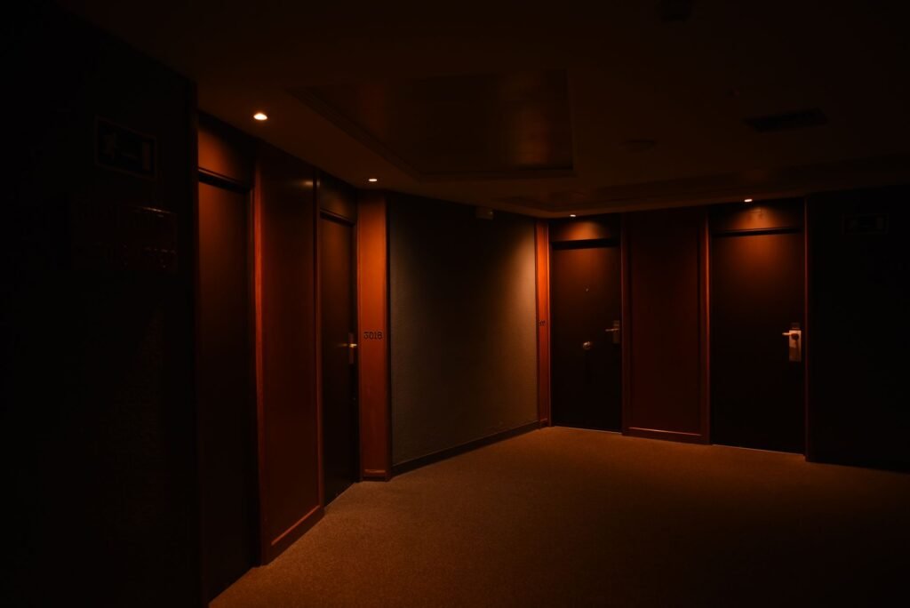 Quiet hotel corridor in the evening with closed doors and warm wall lights