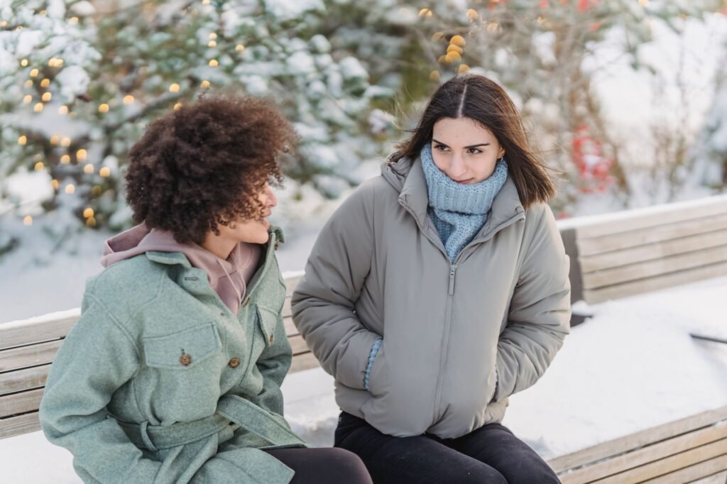 Two adults talking on an outdoor bench in a public setting