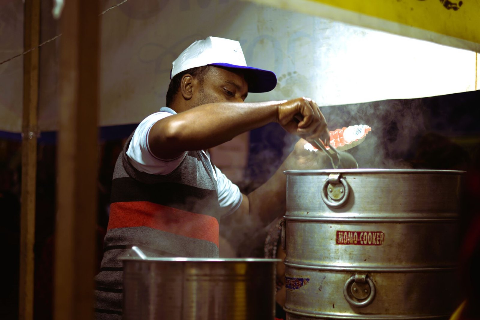 Street vendor cooking food with steamer at night market.