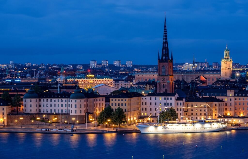 city, cityscape, waterfront, illuminated, ship, architecture, skyline, historic center, church, steeple, water, sea, nature,