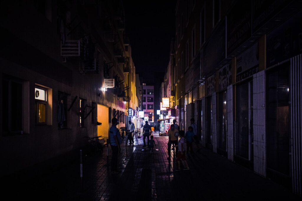 Explore the bustling night scene in Dubai's Bur Dubai with illuminated streets and silhouetted pedestrians.