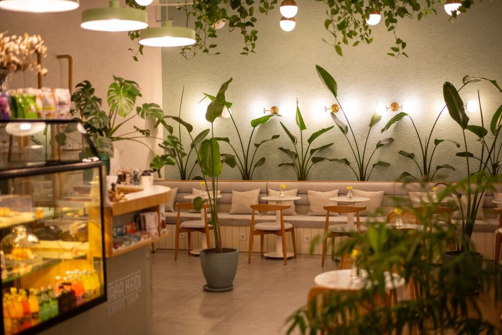 Elegant café interior with plants and warm lighting, creating a cozy ambiance.