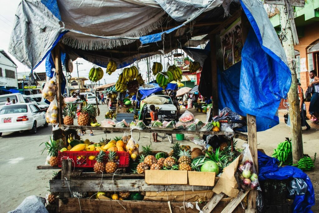 Fresh fruits displayed at a colorful roadside market stall on a busy street.