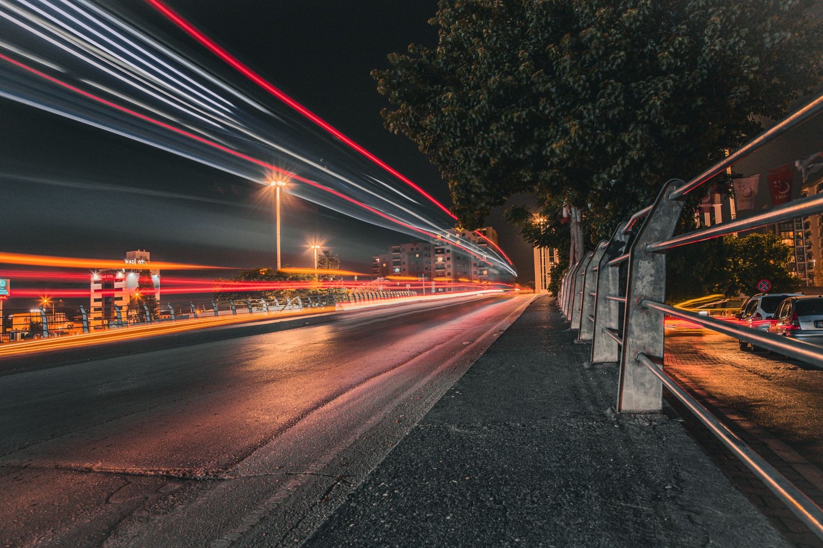 Vivid night-time urban street scene with long exposure light trails creating dynamic motion.