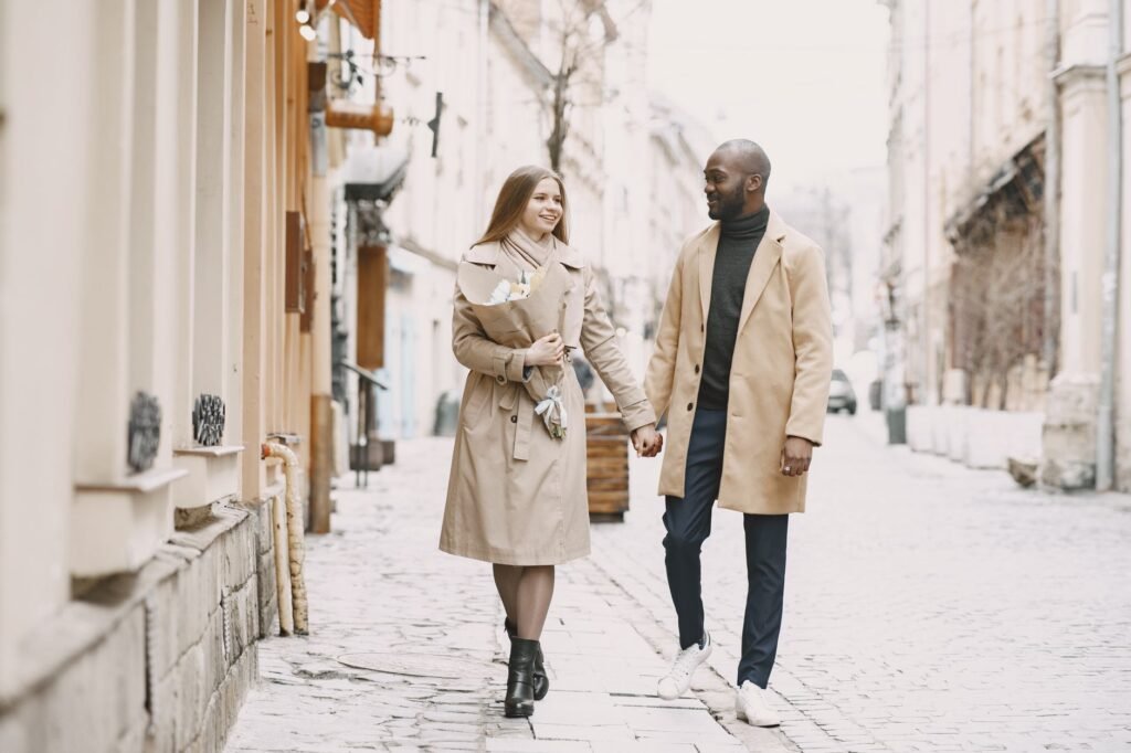 Happy interracial couple enjoying a romantic walk on a picturesque cobblestone street. Perfect for lifestyle content.