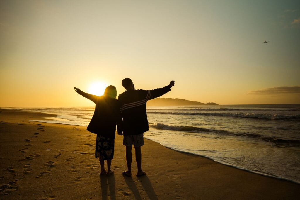 A couple enjoys the sunset on a sandy beach in Brazil, capturing a moment of relaxation and connection.