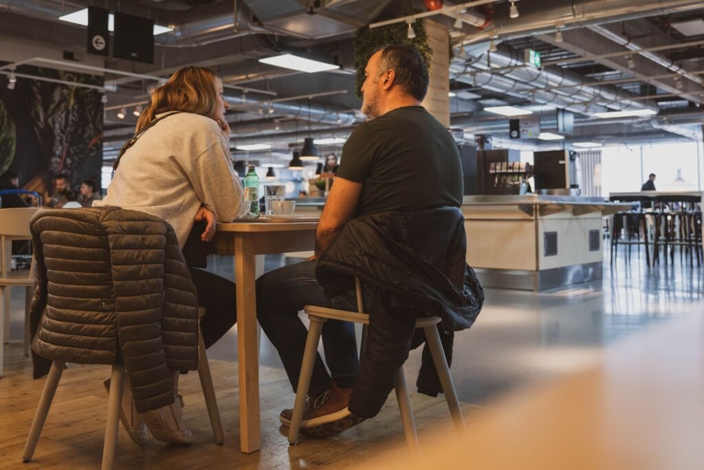 Two adults talking at a bar table while looking at a drinks menu