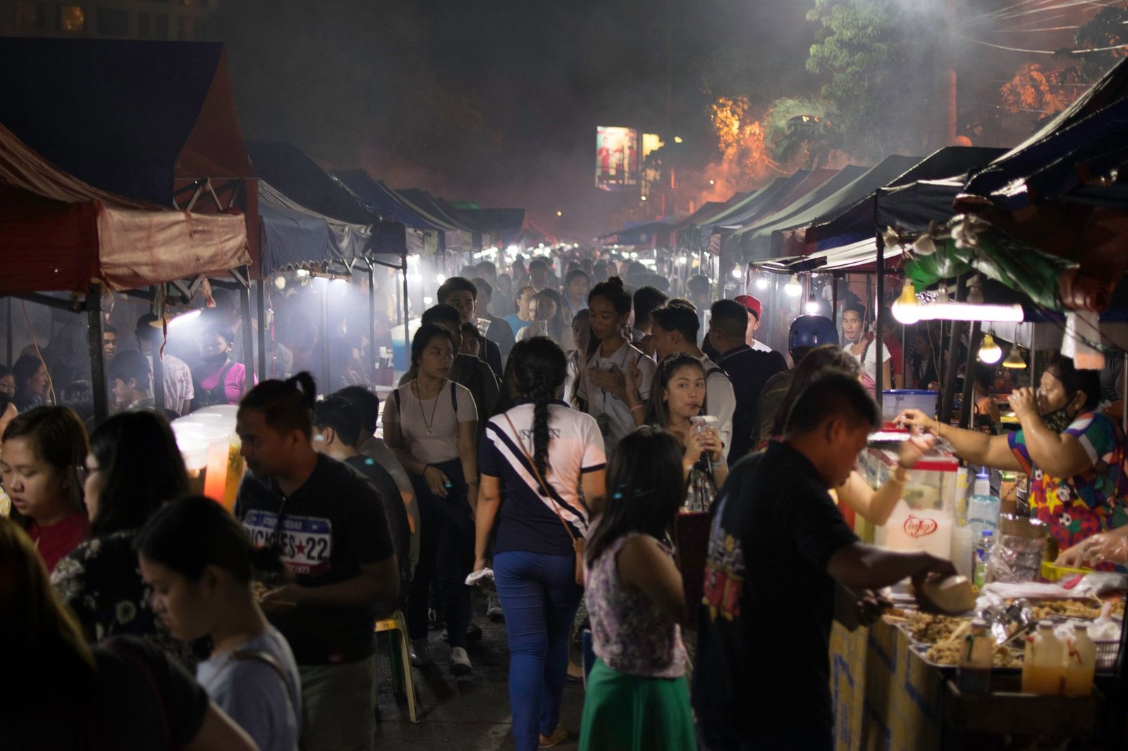 Bustling evening street market filled with people exploring food stalls and vibrant scenes.