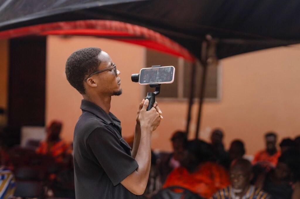 A man uses a smartphone and gimbal to film an event in Kasoa, Ghana.