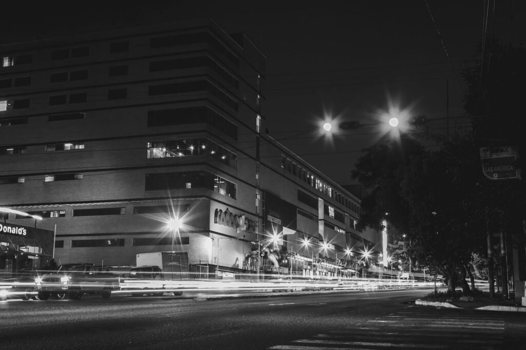 Dramatic urban night photo featuring long exposure light trails and illuminated buildings.
