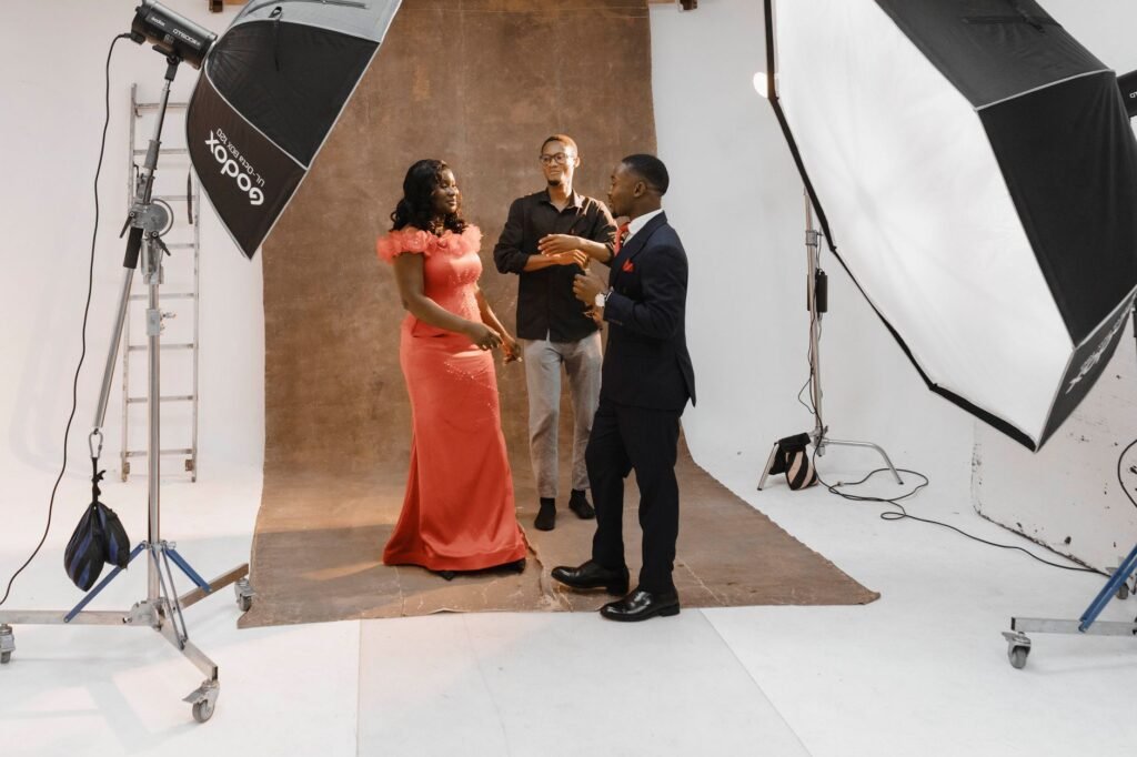 Three adults in a photography studio setting up a portrait shoot.