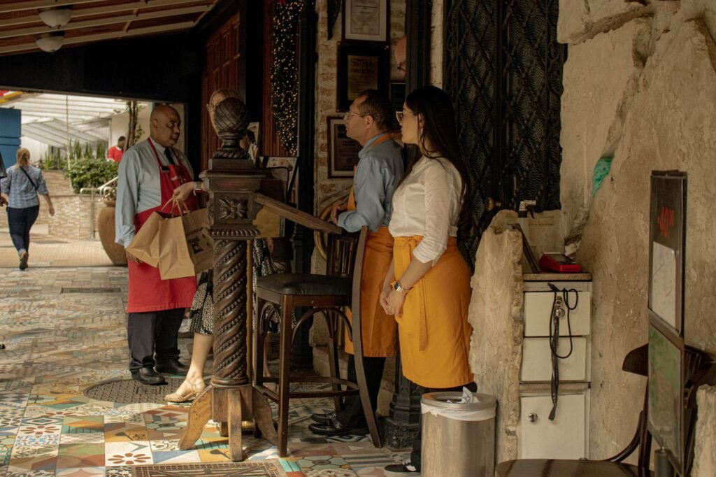 Two people greeting politely outside a small restaurant in the evening