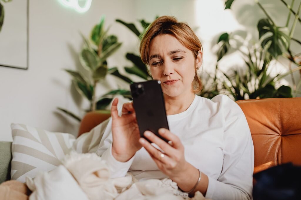 Person holding a smartphone showing a messaging app in a softly lit room