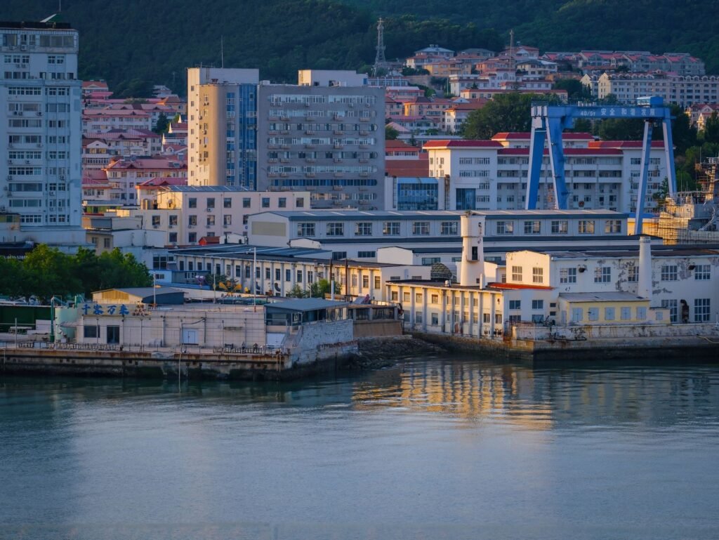 Coastal city skyline at dusk with low-rise buildings and distant harbour cranes
