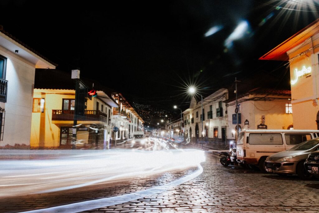 Blurred motion captures bustling night in Cusco city streets with vibrant urban lights.