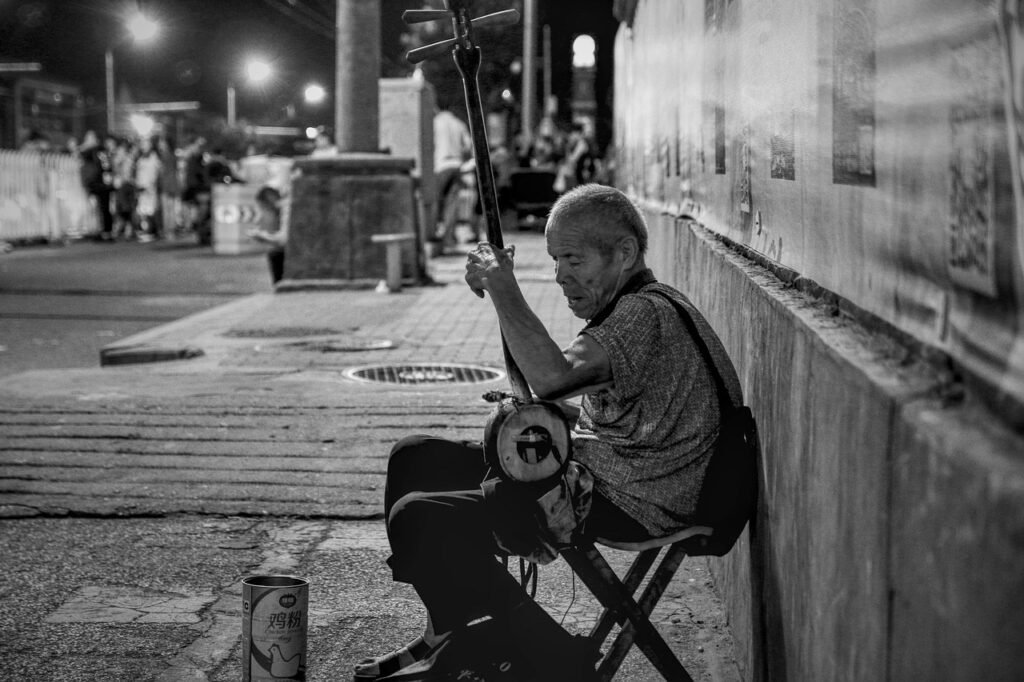 musical player, street, street performer, city, night, evening, black and white