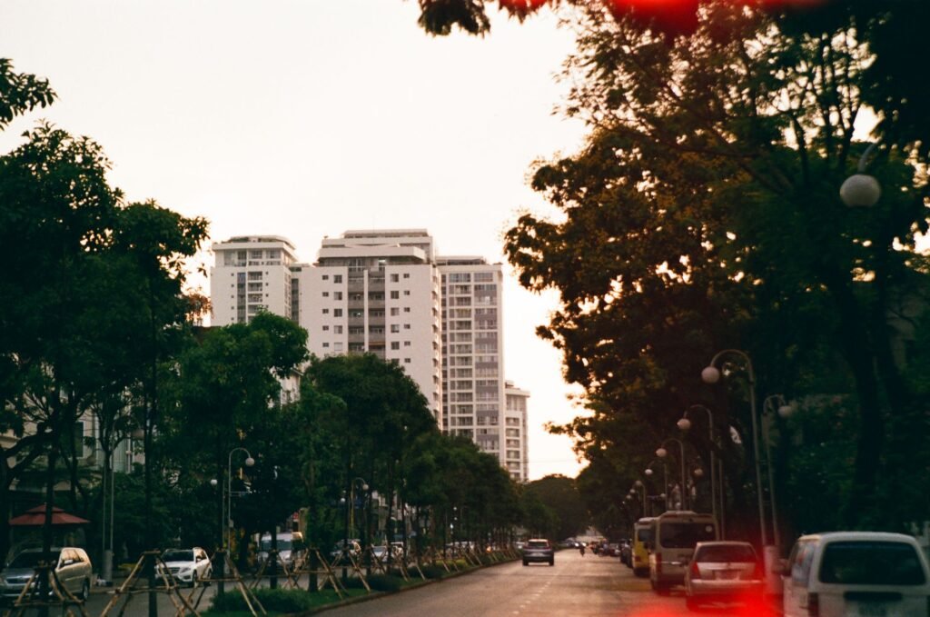 Explore a tranquil urban street in Ho Chi Minh City at twilight, featuring tall buildings and lush trees.