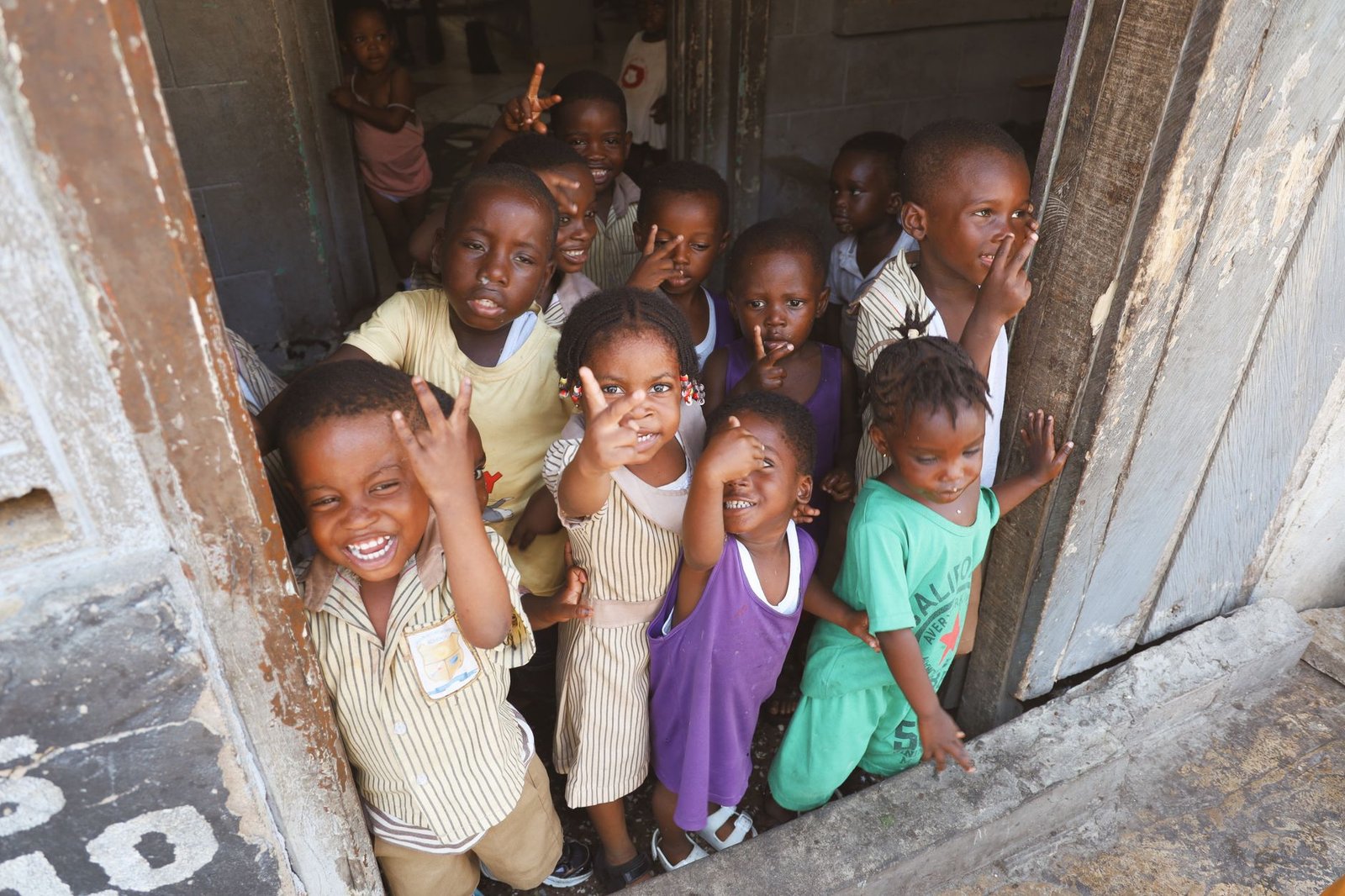 Group of happy children smiling and posing in a doorway in Accra, Ghana, showcasing community and joy.