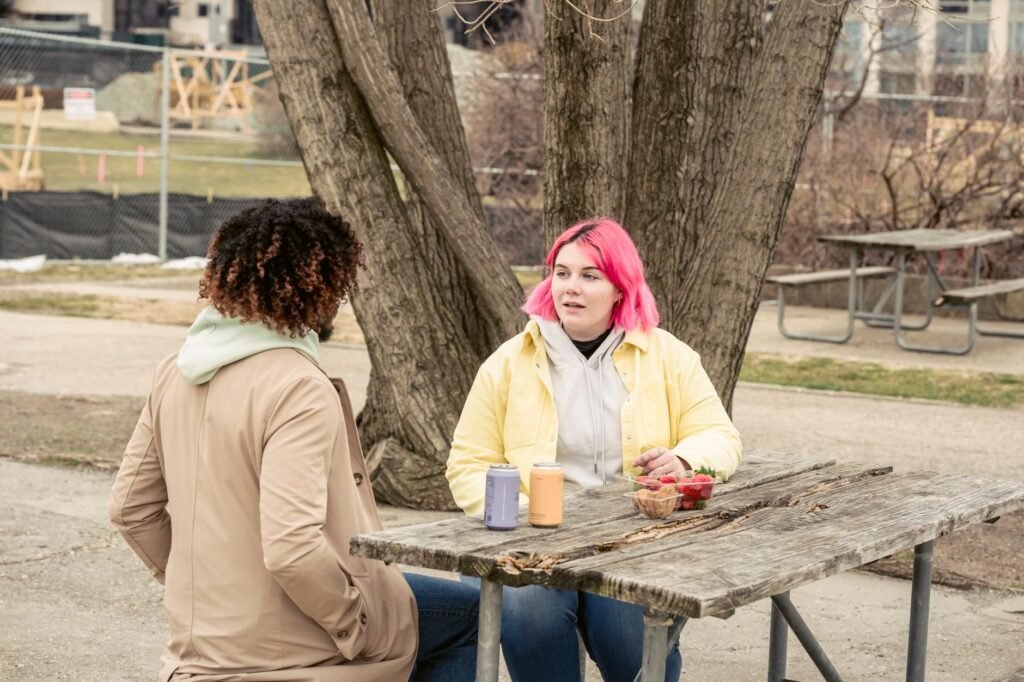 Two people having a relaxed low-key conversation at an outdoor table in a Ghanaian town