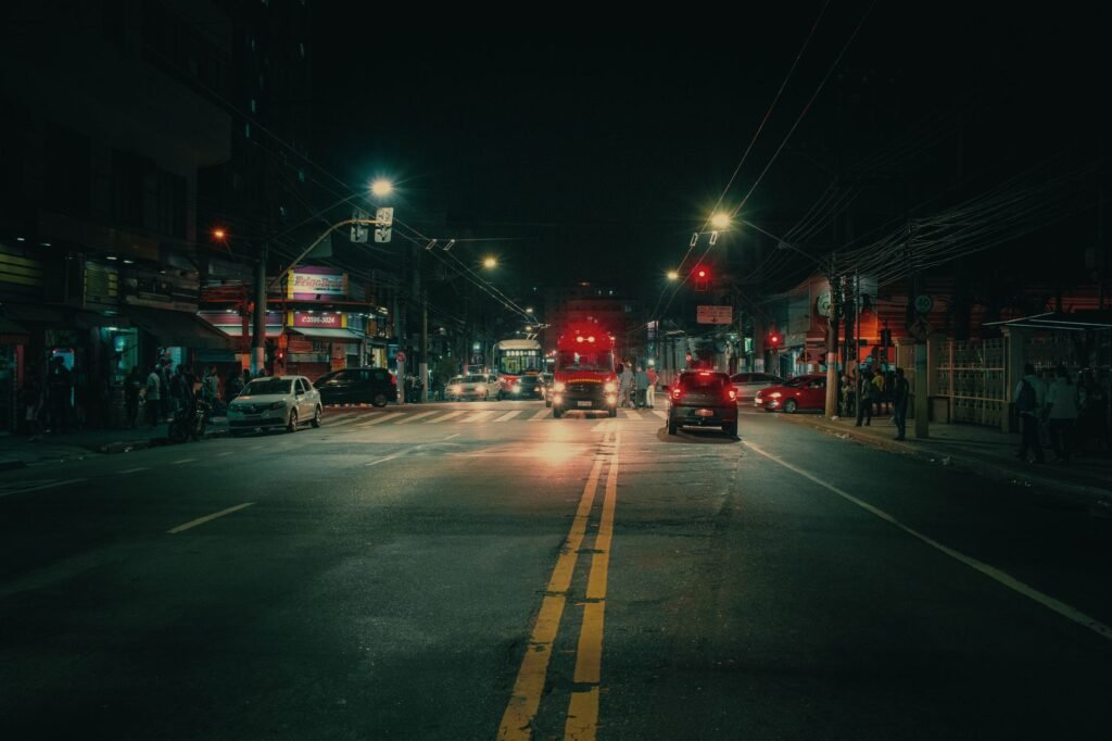 Wide asphalt road with traffic in centre of modern illuminated city at dark night
