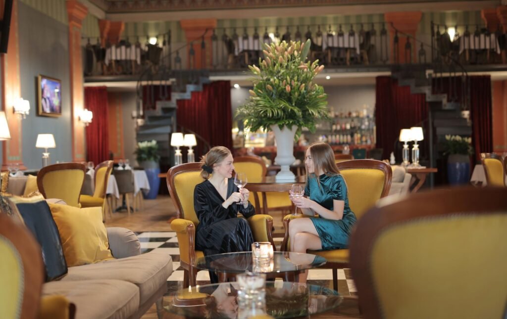 Two women enjoying a conversation in a luxurious hotel lounge setting.
