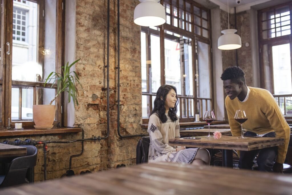 A couple sharing a moment over wine in a cozy, rustic cafe with exposed brick walls.